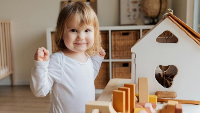 Criança feliz a brincar com casa de madeira e blocos coloridos