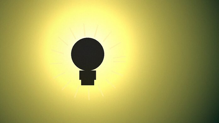Lâmpada incandescente com raios de luz quente em fundo verde