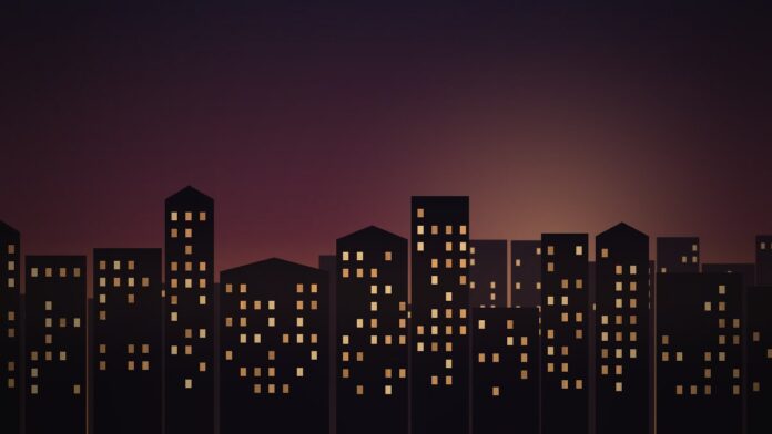 Silhueta de prédios de habitação iluminados ao entardecer em cenário urbano português